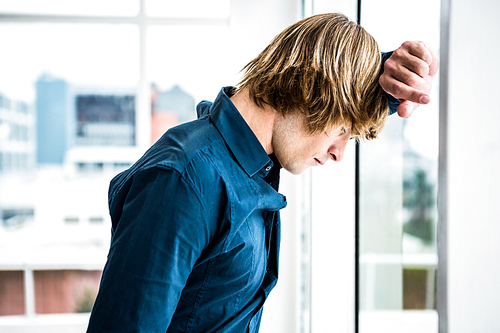 Hipster businessman looking out the window in his office