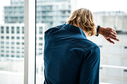 Hipster businessman looking out the window in his office