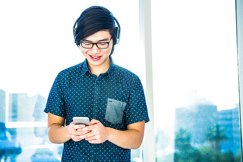 Smiling hipster businessman listening music in his office