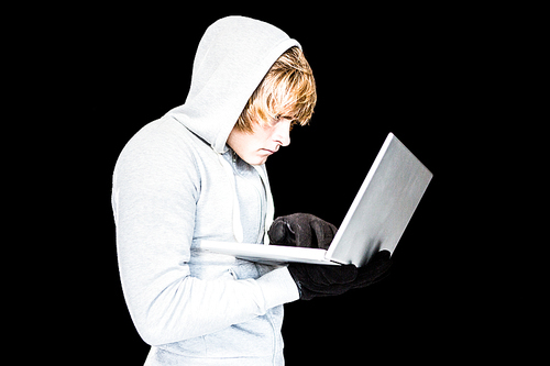 Focused man with hoodie typing on laptop with black background