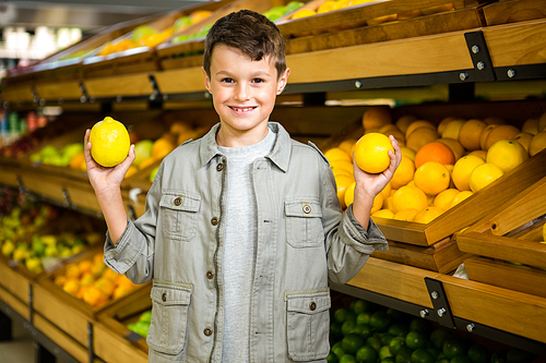 Cute boy holding lemons at the grocery store