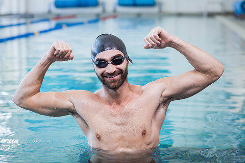 Smiling man triumphing with raised arms at the pool