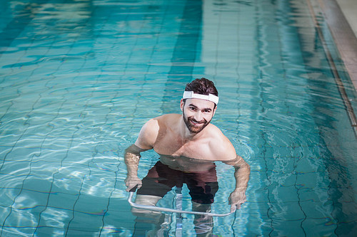 Smiling man doing underwater bike in the pool