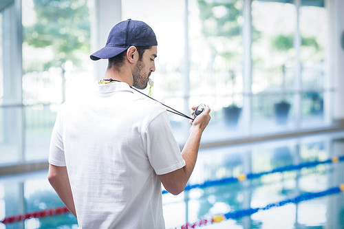 Serious trainer looking at stopwatch at the pool