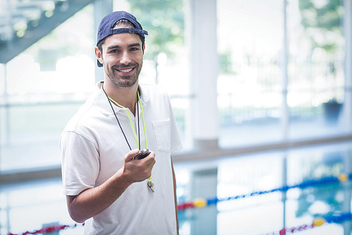 Serious trainer looking at stopwatch at the pool