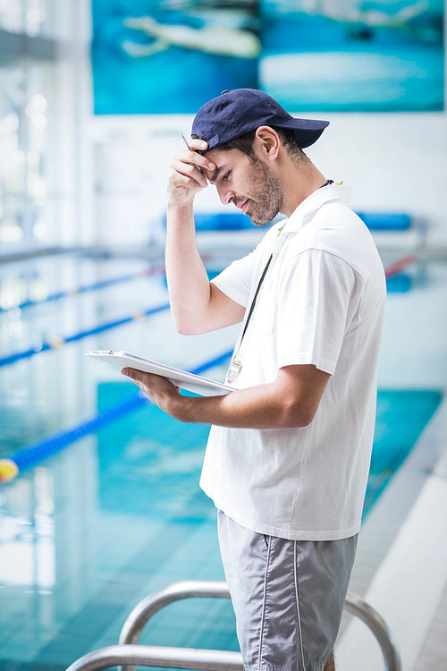 Smiling trainer holding clipboard at the pool