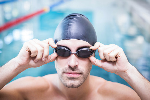 Handsome man wearing swim cap and goggles at the pool