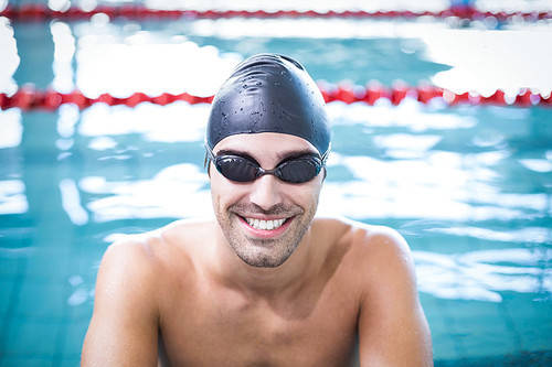 Handsome man wearing swim cap and goggles at the pool