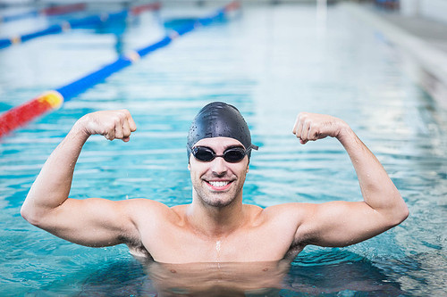 Handsome man triumphing with raised arms in the pool