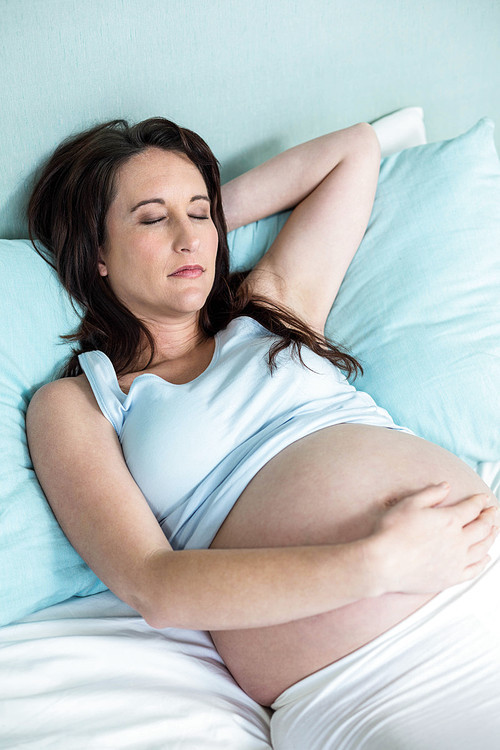 Pregnant woman resting on her bed at home