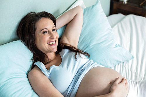 Pregnant woman lying on bed at home