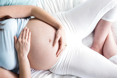 Pregnant woman lying on bed at home