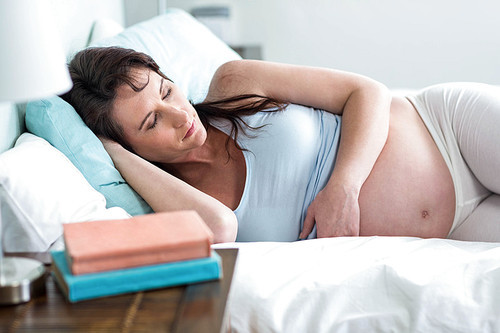 Pregnant woman resting on her bed at home