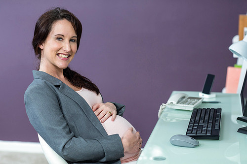 Portrait of smiling pregnant woman in office