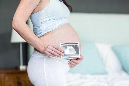 Pregnant woman showing ultrasound scan in bedroom