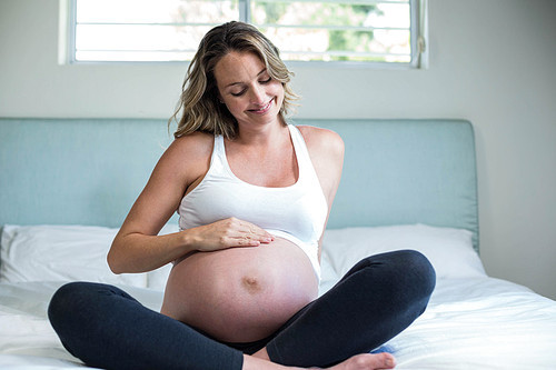 Pregnant woman resting on her bed in her bedroom
