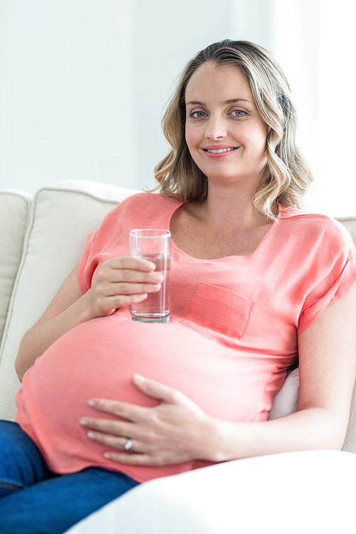 Pregnant woman drinking water in the living room
