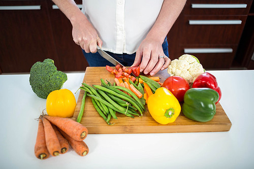 Pregnant woman cutting vegetables in the kitchen