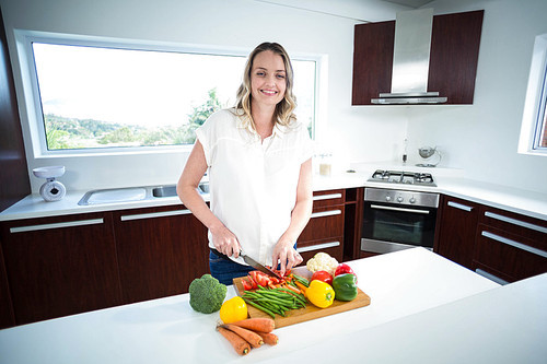 Pregnant woman cutting vegetables in the kitchen