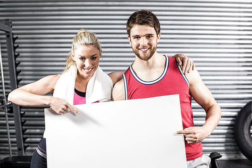 Fit couple holding blank paper at crossfit gym