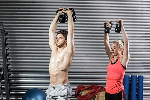 Couple lifting dumbbells together at crossfit gym