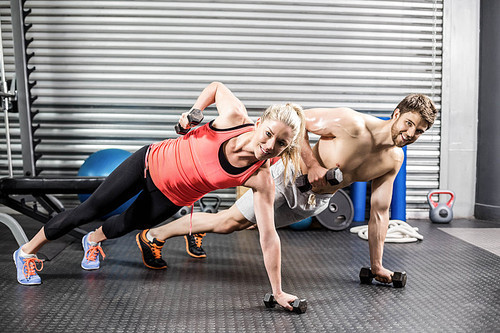 Couple doing push up with dumbbells at crossfit gym
