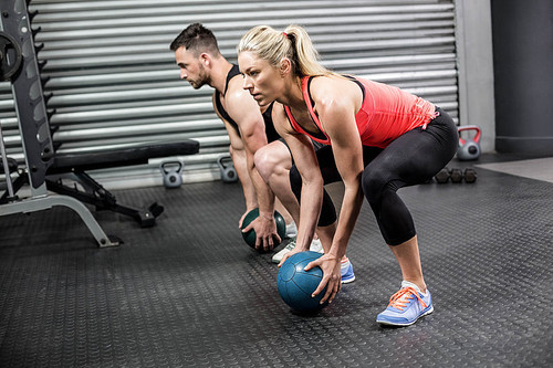 Couple doing ball exercise at crossfit gym