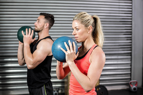 Couple doing ball exercise at crossfit gym
