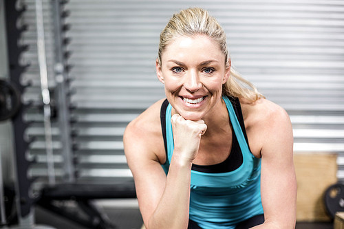 Smiling fit woman sitting at crossfit gym