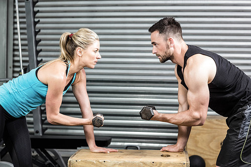 Couple lifting dumbbells together at crossfit gym