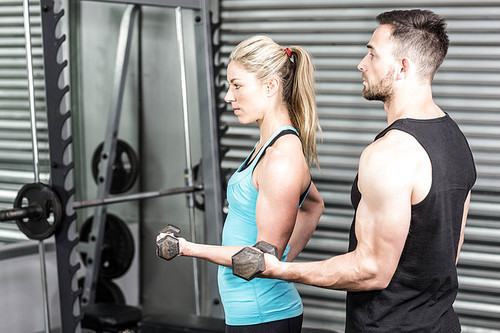 Couple posing with dumbbells at crossfit gym