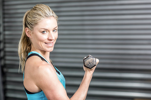 Fit woman lifting dumbbells at crossfit gym