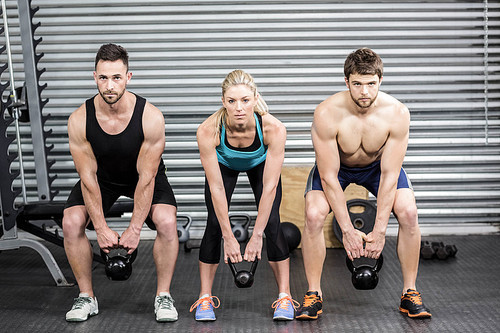 Fit people lifting dumbbells at crossfit gym