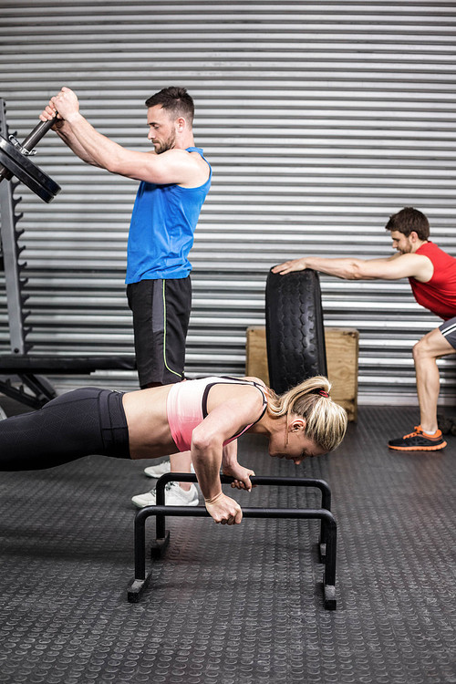 Fit people doing exercises at crossfit gym
