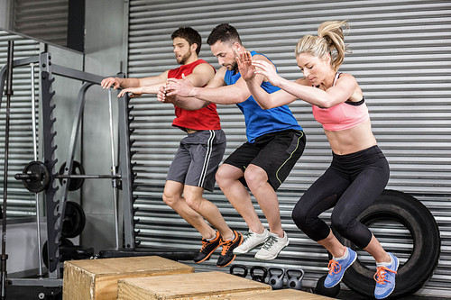 Fit people doing exercises with box at crossfit gym