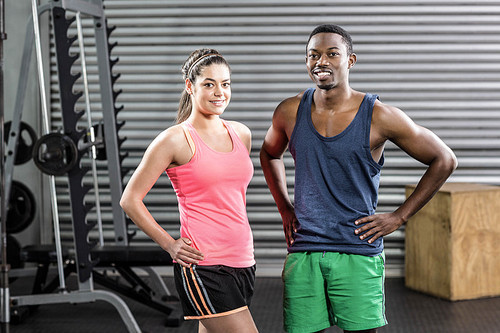 Smiling fit couple posing at crossfit gym