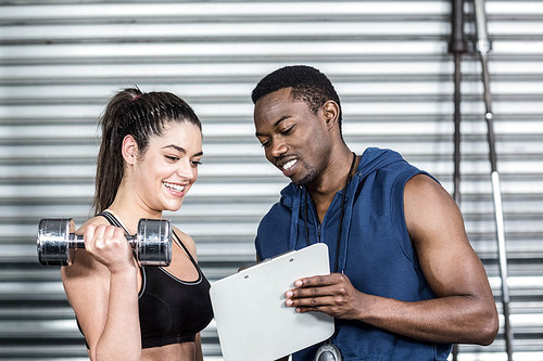 Athletic trainer explaining workout plan to woman at crossfit gym