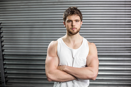 Front view of serious man crossing arms at crossfit gym