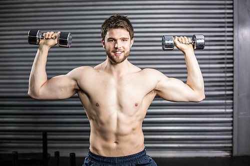 Front view of smiling man lifting weight at crossfit gym