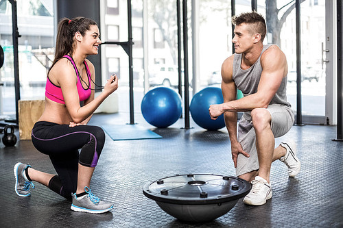 Athletic man working out helped by trainer woman at crossfit gym