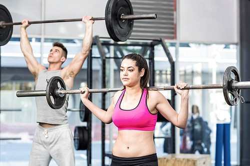 Fit couple lifting barbell at crossfit gym