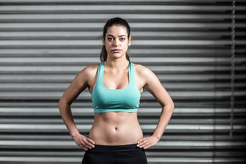 Portrait of fit woman with hands on hips at crossfit gym