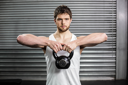 Fit man lifting a dumbbell at crossfit gym