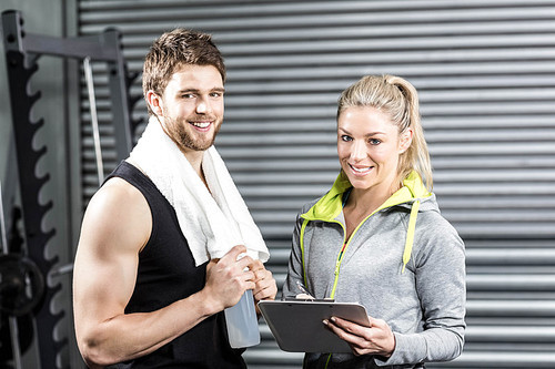 Smiling fit couple taking notes at crossfit gym