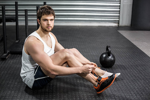 Fit man tying up her shoe laces at crossfit gym