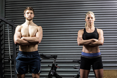 Serious crossfit couple posing at crossfit gym