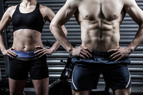 Fit couple with hands on the hips at crossfit gym