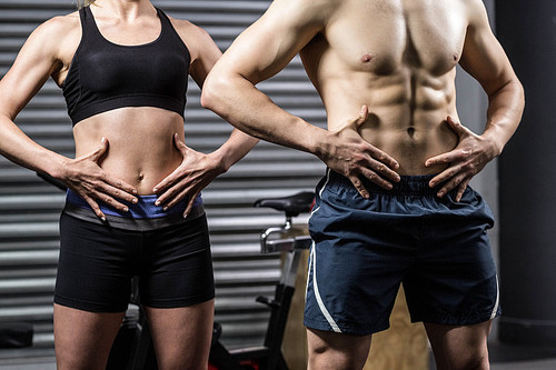 Midsection of fit couple posing at crossfit gym