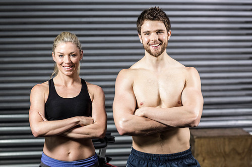 Crossfit couple smilling at the camera at crossfit gym