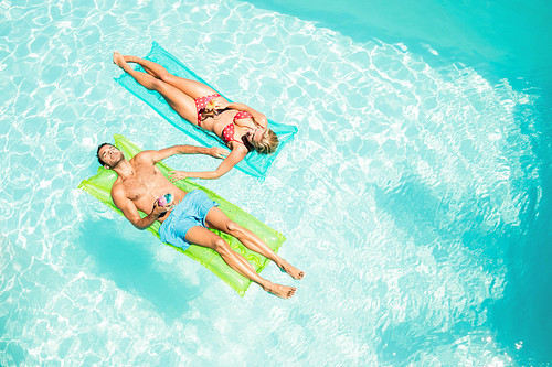 Peaceful couple on lilos holding cocktails in the pool